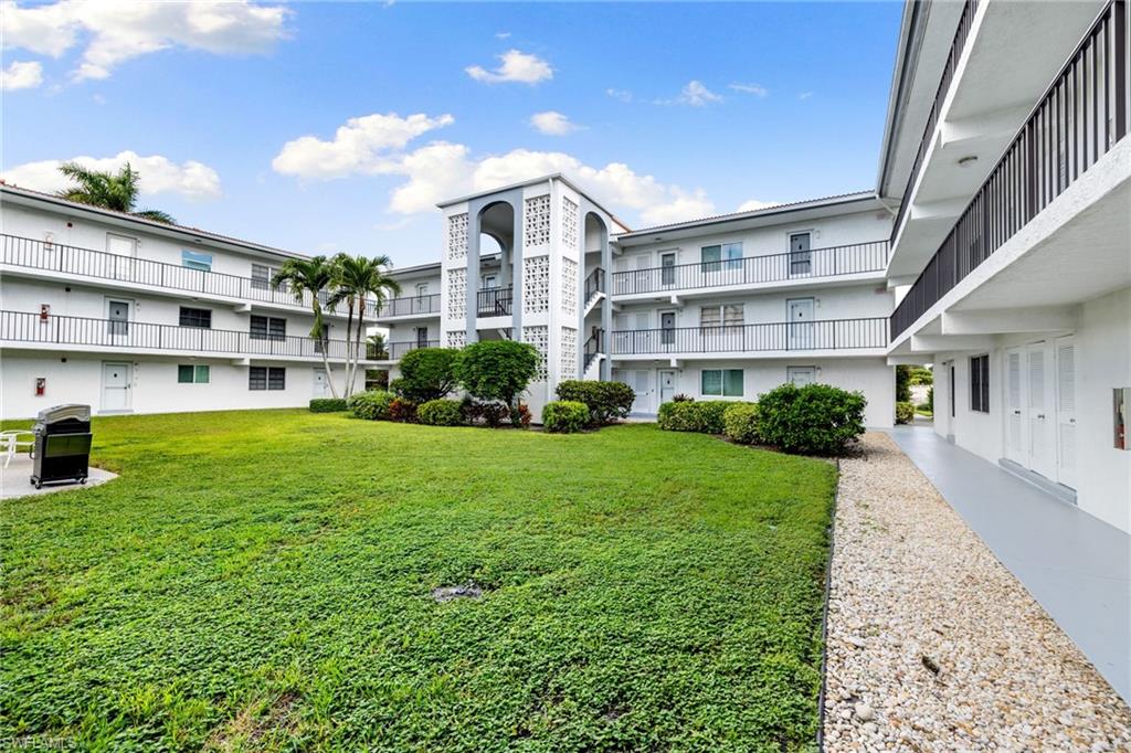 5 High Point Circle West, Unit 307 Naples, FL 34103 - Photo 27 of 31 a front view of a house with garden