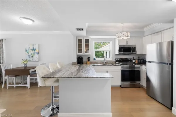 a kitchen with kitchen island granite countertop a refrigerator stove microwave and dining table