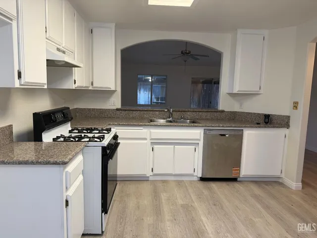 a kitchen with granite countertop a sink stove and cabinets