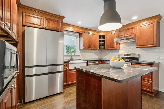 a kitchen with stainless steel appliances granite countertop a refrigerator a sink dishwasher a stove and a refrigerator