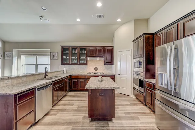 a large kitchen with stainless steel appliances granite countertop plenty wooden cabinets counter space and a sink