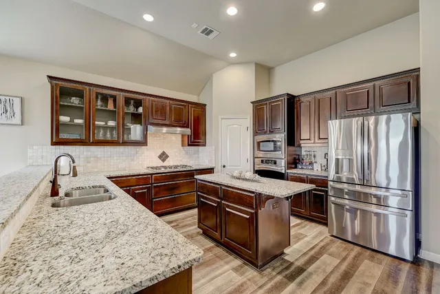 a kitchen with stainless steel appliances granite countertop a stove refrigerator and microwave