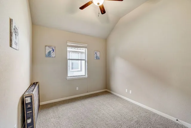 an empty room with ceiling fan and window