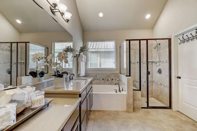 a large spacious bathroom with a tub a double vanity sink a mirror and shower
