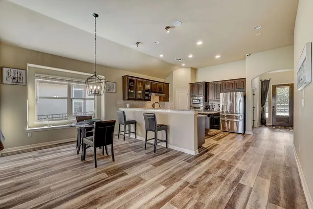 a living room with stainless steel appliances kitchen island granite countertop furniture wooden floor and a window