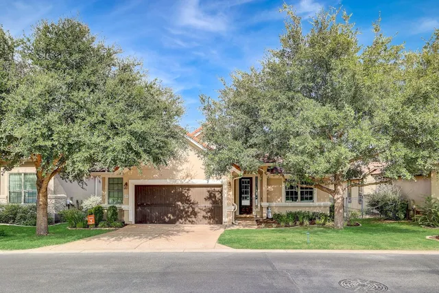 a front view of a house with a garden and trees