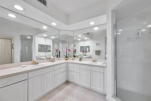 a large white bathroom with a double vanity sink and mirror
