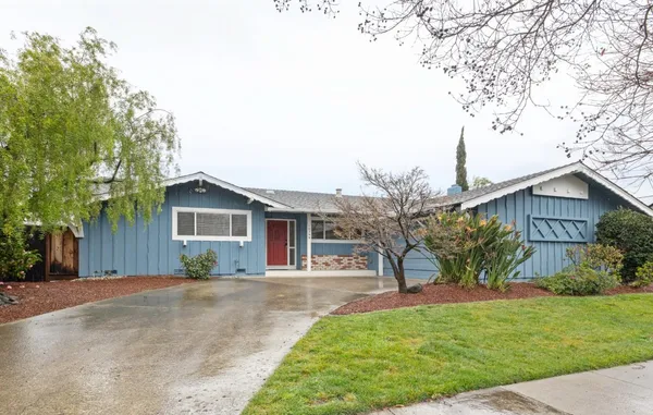a front view of a house with a garden and trees