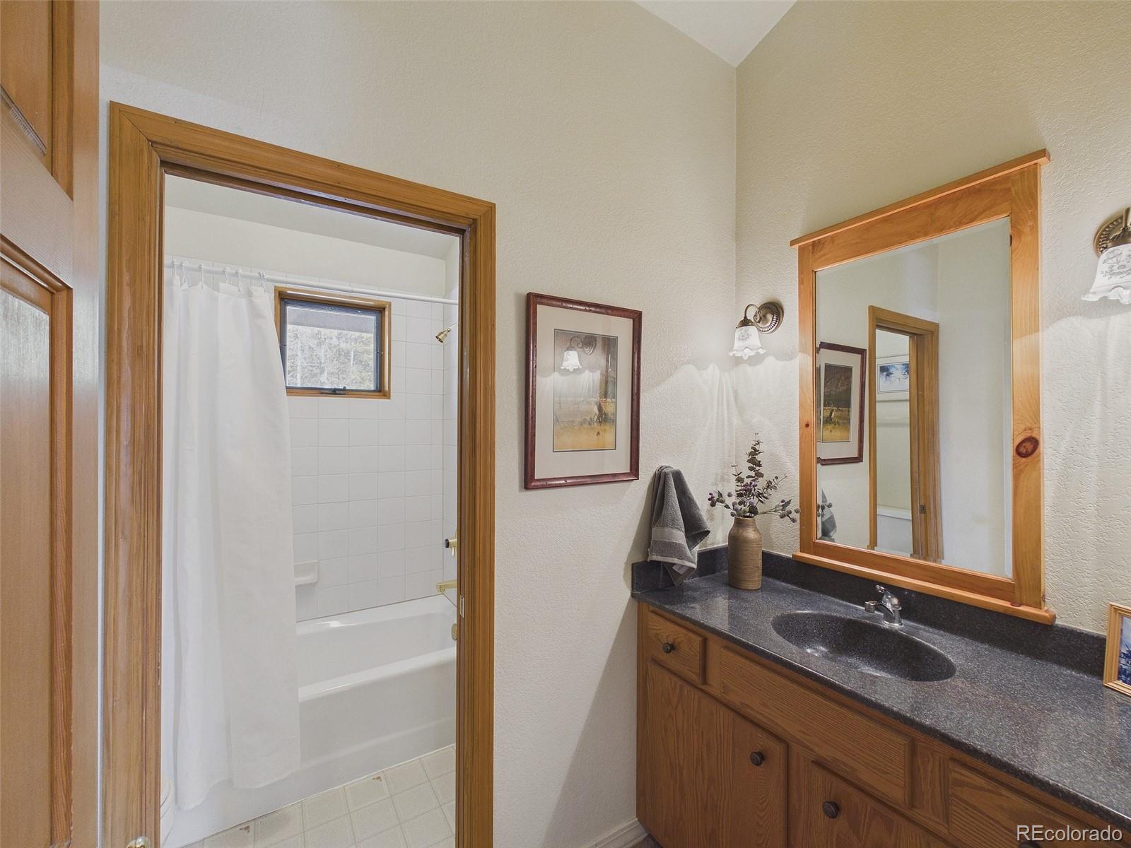 10798 Crystal Way Morrison, CO 80465 - Photo 21 of 36 a bathroom with a granite countertop sink and a mirror