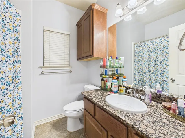 a bathroom with a granite countertop sink a toilet and a mirror