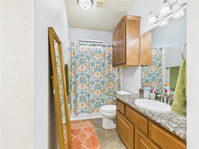 a bathroom with a granite countertop sink toilet and shower