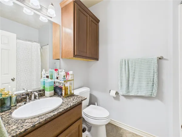 a bathroom with a granite countertop toilet sink and mirror