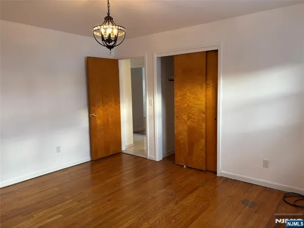 an empty room with wooden floor closet and windows