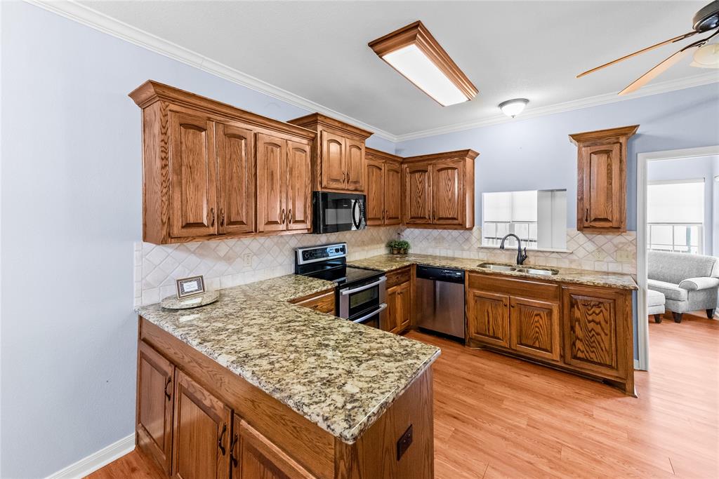 32 North Shore Circle Waco, TX 76708 - Photo 22 of 26 a kitchen with granite countertop wooden cabinets a sink dishwasher stove and wooden cabinets