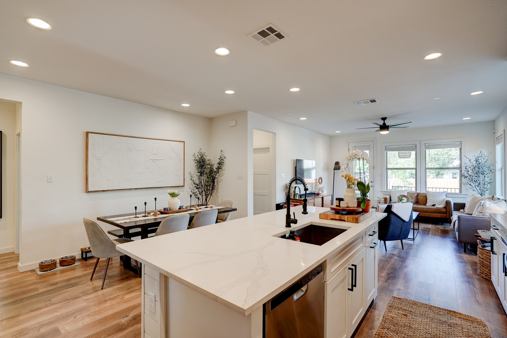 2240 Ringstaff Road Leander, TX 78641 - Photo 7 of 25 Kitchen island featuring a white countertop with an undermount sink and matte black faucet, open to the dining area and living space