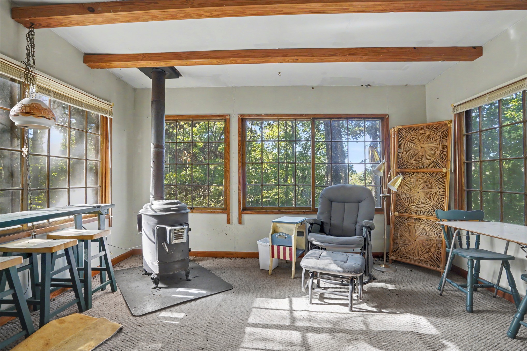 46420 South 590 Road Jay, OK 74346 - Photo 38 of 63 Exposed wood ceiling beams, multiple large grid windows, wood-burning stove, and a suspended light fixture