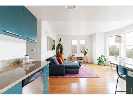 a living room with furniture a large window and wooden floor