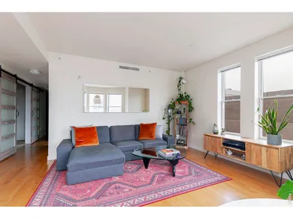 a living room with furniture potted plant and kitchen view
