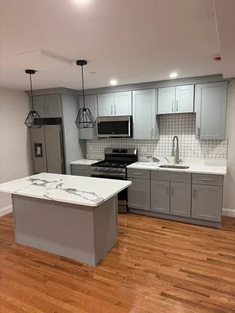 a kitchen with kitchen island a sink a stove a refrigerator and a fireplace
