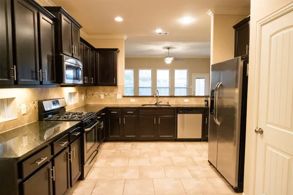 a kitchen with stainless steel appliances granite countertop a stove a sink and a refrigerator