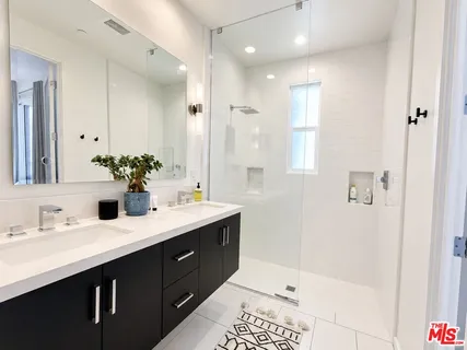 a bathroom with a double vanity sink mirror and shower
