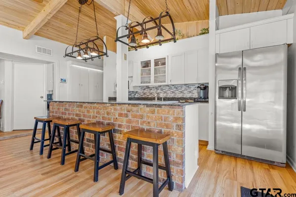 a kitchen with stainless steel appliances granite countertop a dining table chairs refrigerator and sink