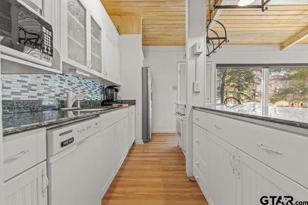 a kitchen with granite countertop white cabinets and white appliances