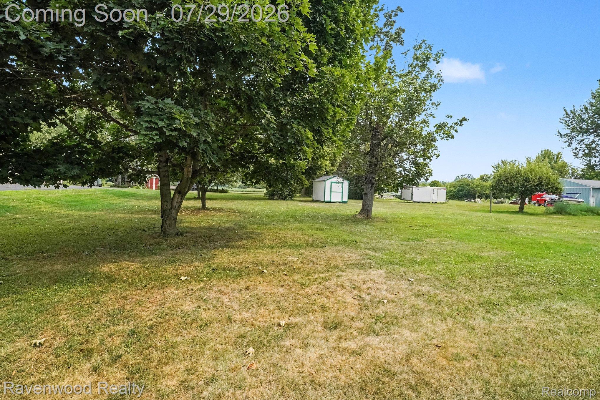 6317 East Coldwater Road Flint, MI 48506 - Photo 27 of 29 Spacious outdoor area featuring mature trees, a detached storage shed with a white exterior and green trim, and an expansive lawn