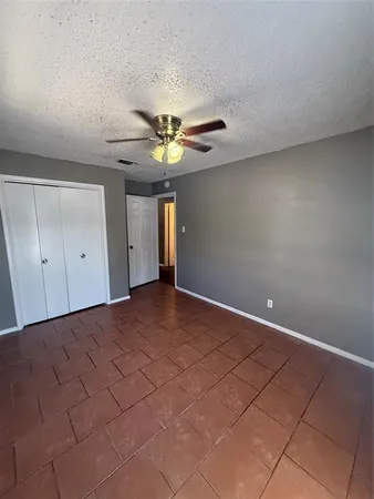a view of an empty room and chandelier fan