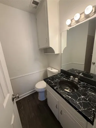 a bathroom with a granite countertop sink and a toilet