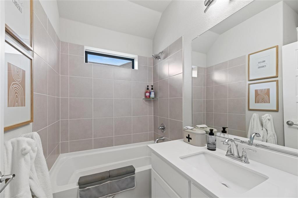 2262 Poppyvine Road Frisco, TX 75033 - Photo 32 of 40 Bathroom featuring a built-in tub with tile surround, a built-in vanity with an integrated sink, polished chrome fixtures, and a horizontal privacy window