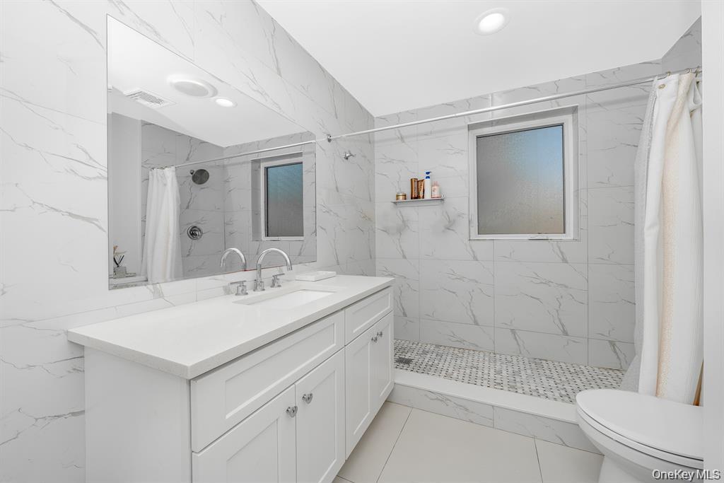 28 Riverside Avenue Amityville, NY 11701 - Photo 19 of 31 a bathroom with a sink a toilet and shower