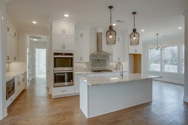 a large kitchen with stainless steel appliances granite countertop a stove a sink and a refrigerator