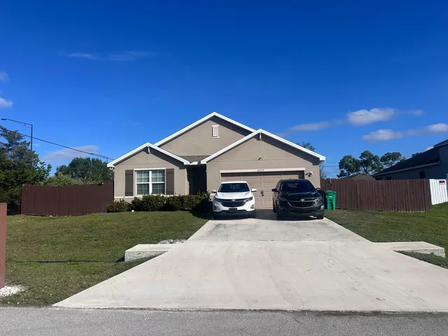 a view of a house with a yard and large tree