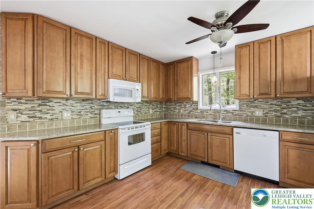 505 Chipmunk Road Bushkill, PA 18324 - Photo 7 of 46 a kitchen with granite countertop white cabinets white appliances a sink and wooden floor