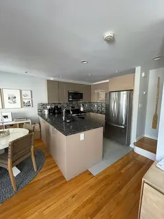 a large white kitchen with wooden floor and stainless steel appliances