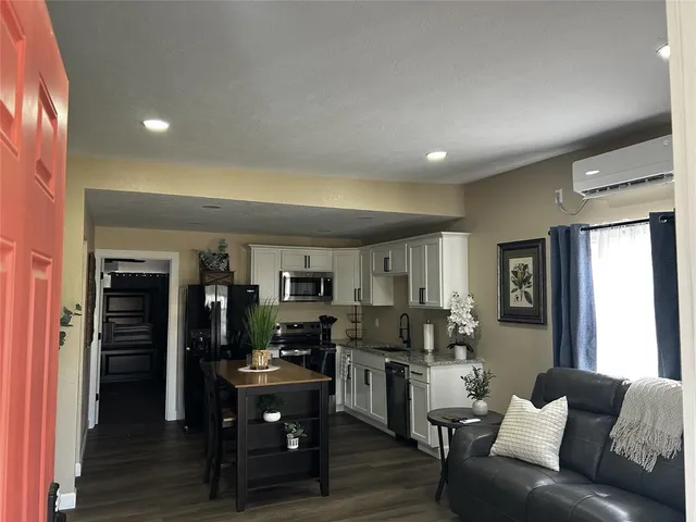a living room with furniture kitchen area and a window