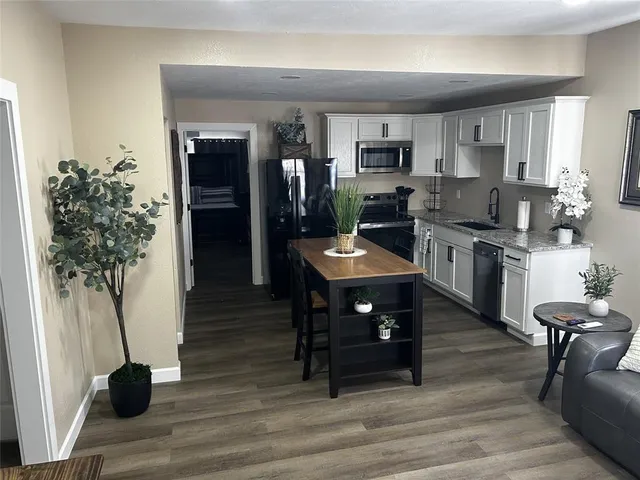 a kitchen with stainless steel appliances kitchen island granite countertop a table chairs in it and white cabinets