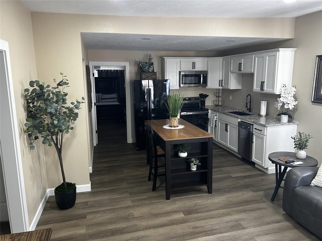 908 West Chestnut Street Denison, TX 75020 - Photo 5 of 19 a kitchen with stainless steel appliances kitchen island granite countertop a table chairs in it and white cabinets