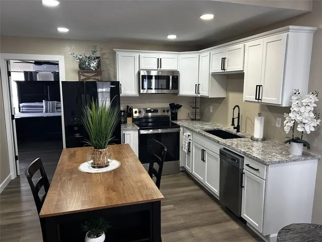 a kitchen with stainless steel appliances kitchen island granite countertop a refrigerator a stove a microwave a sink and cabinets