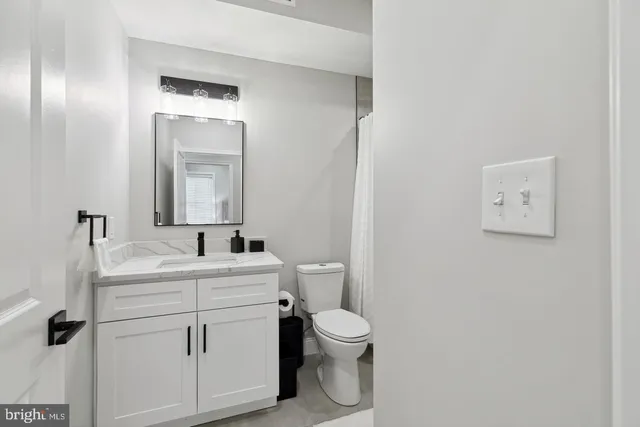 a bathroom with a toilet sink vanity and mirror