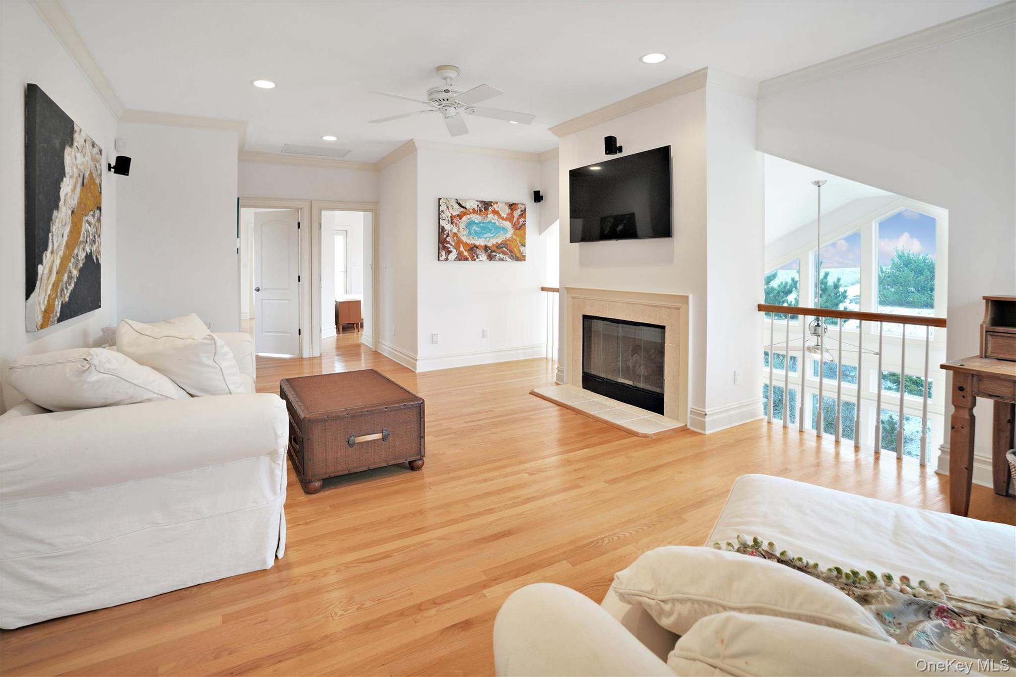 605 Dune Road Westhampton, NY 11978 - Photo 29 of 44 Second Floor Living area with ornamental molding, recessed lighting, light wood-style floors, a ceiling fan, and a glass covered fireplace. Gorgeous Views of Ocean