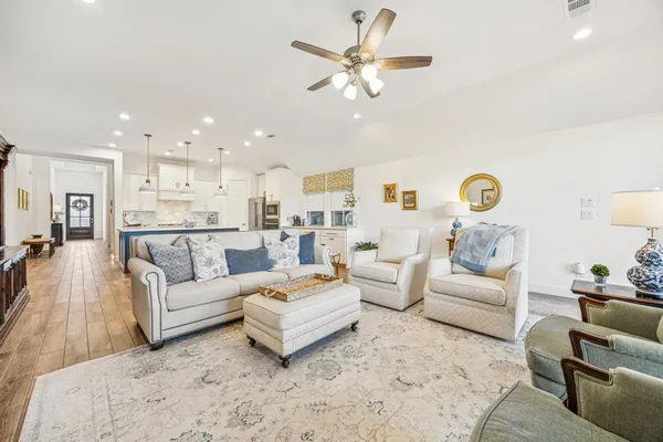 a living room with furniture kitchen view and a chandelier