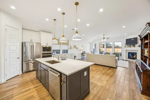 a kitchen with stainless steel appliances a stove a sink a refrigerator and a fireplace