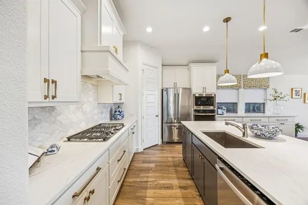 a kitchen with stainless steel appliances a sink a stove a refrigerator and cabinets