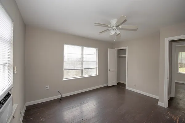 an empty room with windows and fan