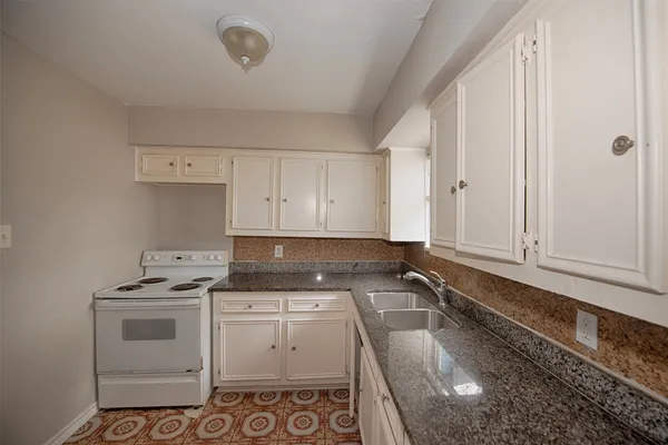 a kitchen with granite countertop white cabinets and white appliances