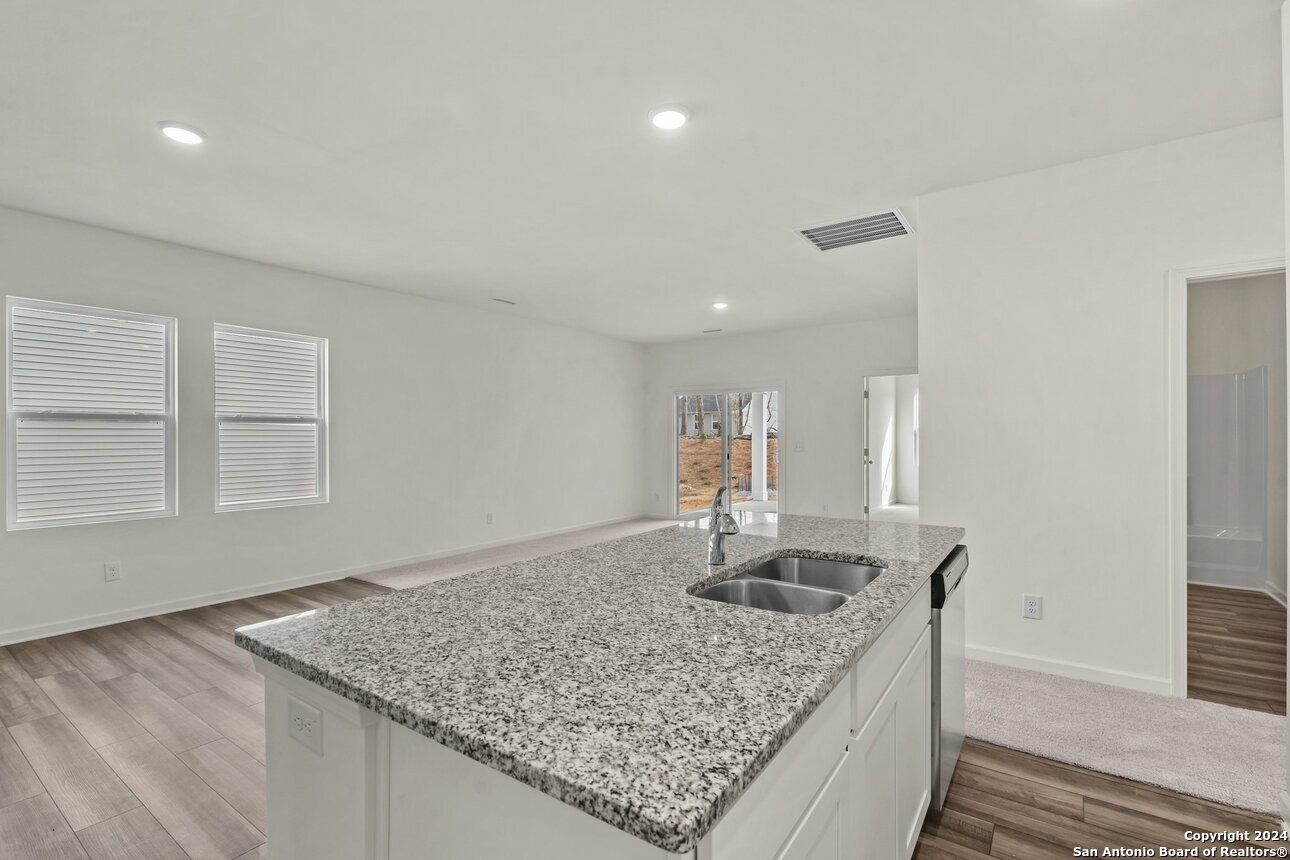 128 Dionicio Loop Seguin, TX 78155 - Photo 8 of 10 a kitchen with kitchen island granite countertop a sink a counter top space and cabinets