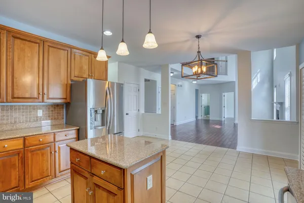 a kitchen with stainless steel appliances granite countertop a refrigerator a sink dishwasher a stove and white cabinets with wooden floor