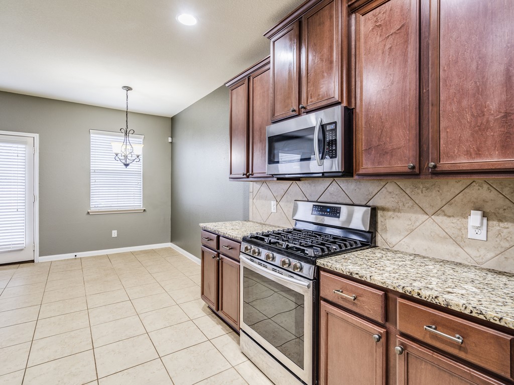 216 Isabel Lane Kyle, TX 78640 - Photo 12 of 27 a kitchen with granite countertop stainless steel appliances a stove sink and microwave